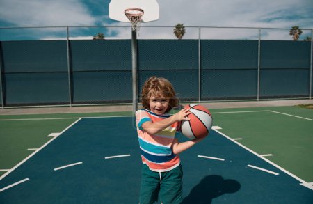 Foto de Lindo niño jugando baloncesto. Niño jugando baloncesto con pelota de baloncesto. Escuela de baloncesto para niños - Imagen libre de derechos
