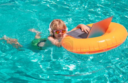 Photo for Happy little boy learning online computer laptop. Child relax and rest on colorful inflatable ring using computer in swimming pool. Little business man in summer vacation trip - Royalty Free Image