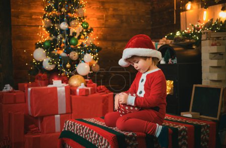 Photo for Christmas attributes. Present box. Childhood moments. Xmas tree. Christmas interior. Little boy decorating xmas tree and opening presents. Christmas gifts - Royalty Free Image