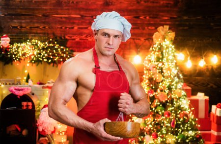 Photo for Sexy Santa Cooking, haute cuisine food for Christmas. Male chef cook decorating New Year dish. Young muscular man wearing Santa hat cooking - Royalty Free Image