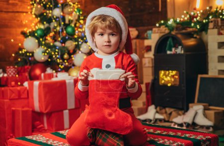 Photo for Christmas stockings, Little boy with Christmas presents in sock. Happy new year. Indoor. Merry and bright christmas. Childhood memories. New Year. Lovely baby enjoy holidays - Royalty Free Image