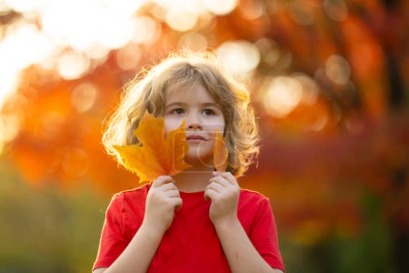 Photo for Close up kids face on golden sunset bathes the scene in warm autumn light. Autumn portrait of cute child outdoor. Childs Autumn Adventure in the Park. - Royalty Free Image