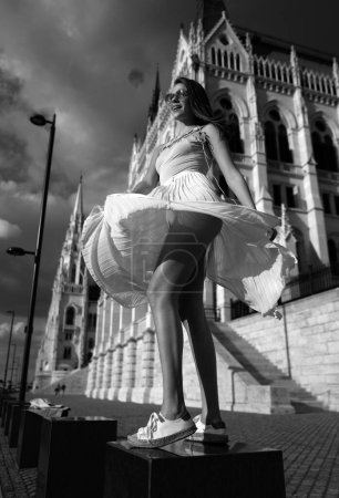 Foto de Hermoso movimiento de mujer en falda en ropa de primavera de verano de moda al aire libre. Emocionado mujer modelo elegante caminando calle de la ciudad. Tendencia de verano, ropa de moda. Budapest ciudad - Imagen libre de derechos