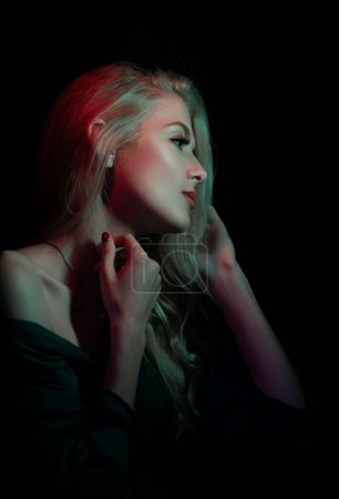Foto de Elegante joven posando sobre fondo negro. Luz y sombra. Retrato de una cara de perfil de mujer de belleza - Imagen libre de derechos