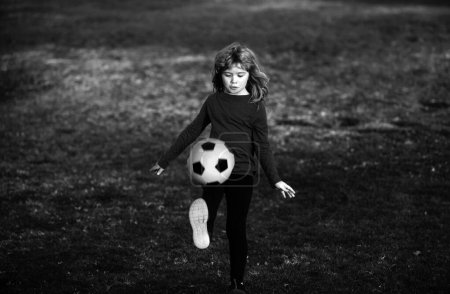 Téléchargez les photos : Enfant garçon jouant au football sur le terrain de football. Un gamin qui joue au foot. Concept de sport pour enfants - en image libre de droit
