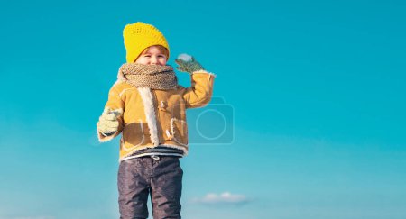 Foto de Niño niño lanzando bola de nieve en invierno al aire libre. Niño feliz con bola de nieve sobre fondo de nieve - Imagen libre de derechos
