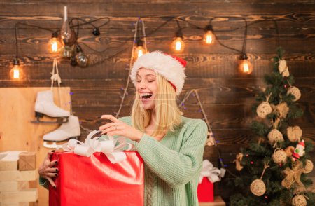 Foto de Decoraciones navideñas y caja de regalo sobre fondo de madera. Verdaderas emociones. Mujer joven con cajas de regalo de Navidad delante del árbol de Navidad - Imagen libre de derechos