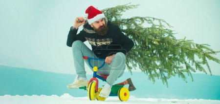 Téléchargez les photos : Homme drôle sur vélo soignant arbre de Noël. Homme avec bonhomme de neige sur fond d'hiver extérieur. Bonhomme de neige pour bannière d'hiver. Père drôle sur les enfants vélo tenir arbre de Noël - en image libre de droit