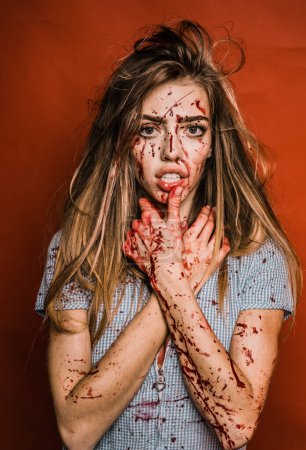 Aggressive girl in blood. Bloody mess. Halloween woman on red background isolated. A terrible Halloween