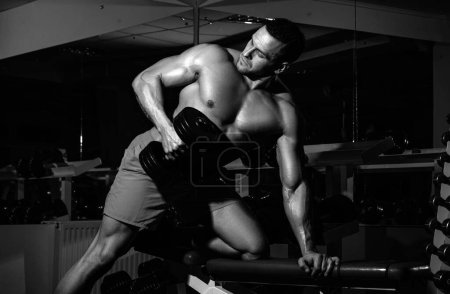 Téléchargez les photos : Sport homme homme faisant biceps levage dans une salle de gym. Portrait de jeune athlète faisant de l'exercice avec haltère au gymnase. Sport et mode de vie sain concept - en image libre de droit