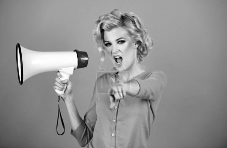 Photo for Megaphone and women. Portrait of pinup girl shouting. Young excited blonde woman screaming hot news, shouting in megaphone isolated on color background studio. Girl pointing finger to the front - Royalty Free Image