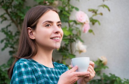 Téléchargez les photos : Portrait de jolie jeune femme dans le parc avec tasse de café pendant la journée d'été. Femme romantique avec tasse de café - en image libre de droit