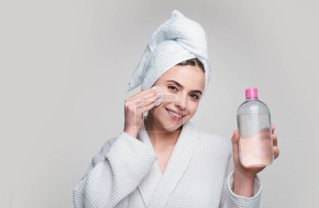 Photo for Beautiful woman delicately moisturizes skin with cosmetic tonic. Portrait of lady with healthy skin without makeup on isolated background. Micellar water - Royalty Free Image