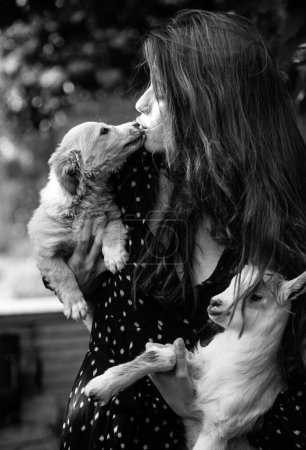 Photo for Woman hugging pet puppy dog and goatling yeanling. Natural young woman. Virgin girl in village. Sprinf fashion portrait of beautiful woman holding a small lamb and dog - Royalty Free Image