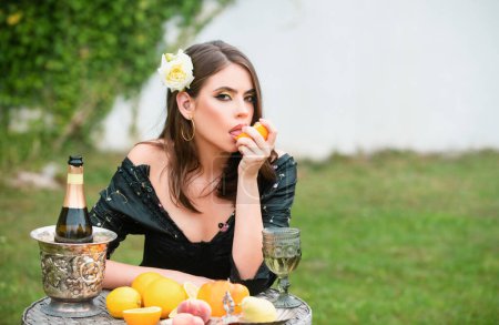 Photo for Young sensual girl eating orange outdoors. Beautiful woman enjoying spring, pretty girl relaxing outdoor. Sexy woman squeezing juice from fresh orange - Royalty Free Image