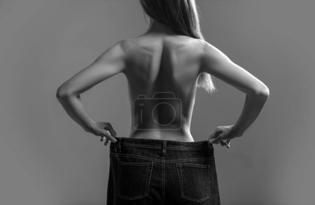 Photo for Woman showing weight lost. Slim girl wearing oversized pants. Woman shows weight loss. Dieting. Woman showing slim body after sport trainings, healthy eating - Royalty Free Image