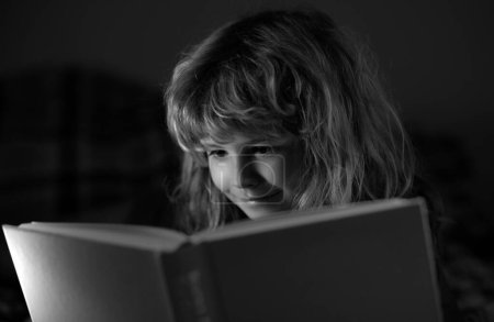 Foto de Lindo niño leyendo un libro. Niño con libro abierto. Lección de escuela en casa. Un niño concentrado en la cama leyendo libros en casa. Concepto de imaginación o aprendizaje - Imagen libre de derechos