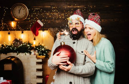 Téléchargez les photos : Couple amoureux de la bombe de Noël devant l'arbre de Noël. Un homme de Noël tient la bombe. Boum créatif - en image libre de droit
