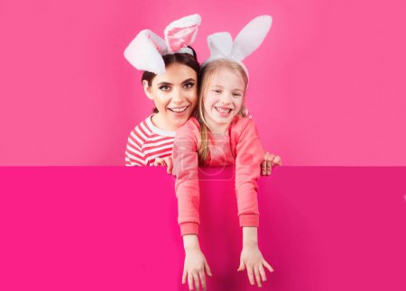 Foto de Feliz infancia. Chicas con orejas de conejo. Los niños hermanitos celebran la Pascua. Caza de huevos. Vacaciones de primavera - Imagen libre de derechos