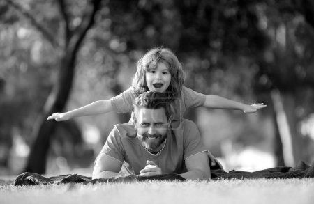 Photo for Father piggyback his little son outside, lying on grass. Fathers Day concept - Royalty Free Image