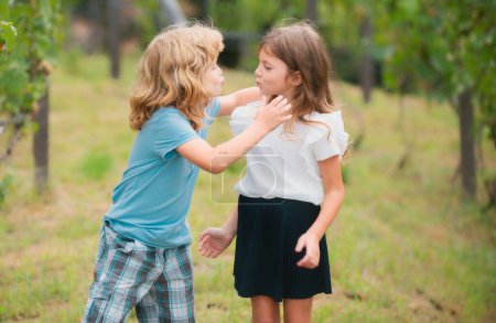 Photo for Adorable happy kids outdoors on summer day, little boy kissing a girl. Lovely little boy and girl, have fun and hugging outdoor. Funny kids face - Royalty Free Image