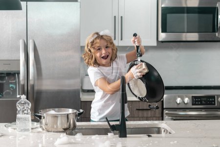 Téléchargez les photos : Enfant laver la vaisselle dans l'évier de la cuisine - en image libre de droit