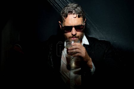 Téléchargez les photos : Homme ivre en costume dans la salle de bain après la soirée. Un ivrogne tient du whisky. Concept alcool et drogues. Fatigué homme d'affaires ivre stressé sous la douche dans le bain. La vie nocturne. Dépendance à l'alcool - en image libre de droit