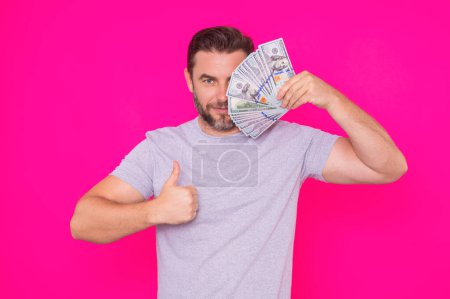 Foto de Hombre de negocios en camiseta con billetes de dinero en efectivo aislados en el fondo del estudio rosa. Billete de cien dólares, concepto financiero - Imagen libre de derechos