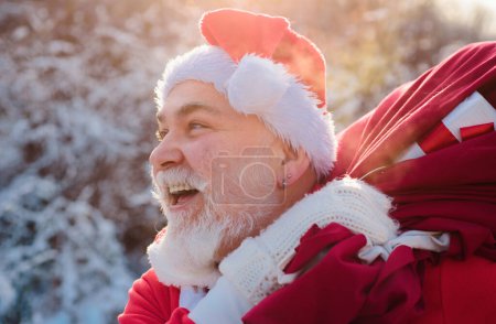 Foto de Santa Claus llegando al bosque de invierno con una bolsa de regalos, paisaje de nieve - Imagen libre de derechos