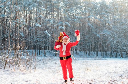 Foto de Feliz Santa Claus llegando al bosque de invierno con una bolsa de regalos, paisaje de nieve - Imagen libre de derechos