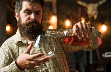 Foto de Degustación degustación de whisky caro. Hombre barbudo con un vaso de whisky. Modelo masculino bebiendo brandy o coñac. Bebida cara - Imagen libre de derechos