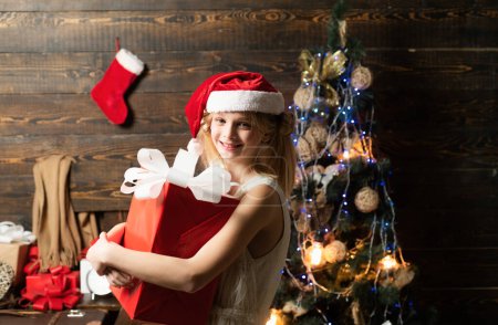 Photo for Merry Christmas and Happy Holidays. Teenager Christmas. Christmas Xmas winter holiday concept. Cute little girl is decorating the Christmas tree indoors - Royalty Free Image