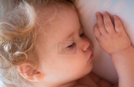Photo for Cute baby child sleeping in the bed. Closeup sleepy kids face - Royalty Free Image