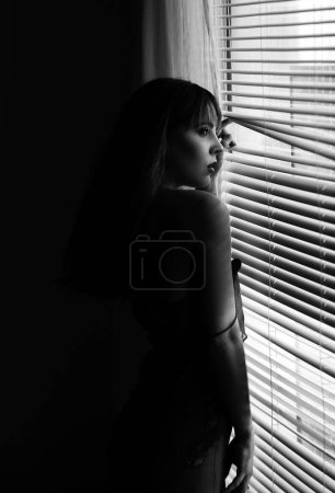 Photo for Beautiful lady by the window. Sensual young woman. Cute girl in a beautiful position. Interior hotel room with large windows - Royalty Free Image
