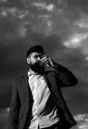 Photo for Man with beard and mustache holds alcoholic beverage on sky background. Service and alcoholism concept - Royalty Free Image