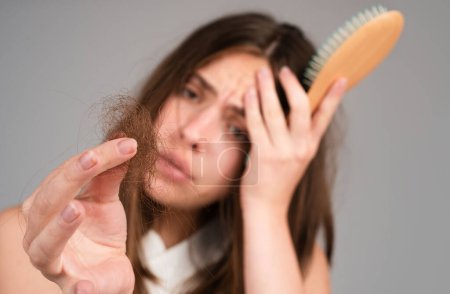 Photo for Woman with hair loss problem. Portrait of Young girl with a bald. Head shot of a nervous girl with a hairbrush - Royalty Free Image