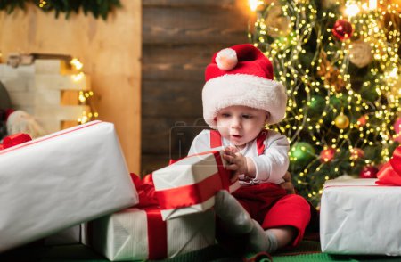 Foto de Retrato navideño de lindo bebé en sombrero de santa. Cara de niños sorprendidos. Niño divertido Año Nuevo - Imagen libre de derechos