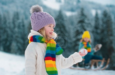 Téléchargez les photos : Petite fille et garçon profitant d'une journée à jouer dans la forêt d'hiver. Enfants frères et sœurs s'amusant dans un beau parc d'hiver. Bonne enfance - en image libre de droit