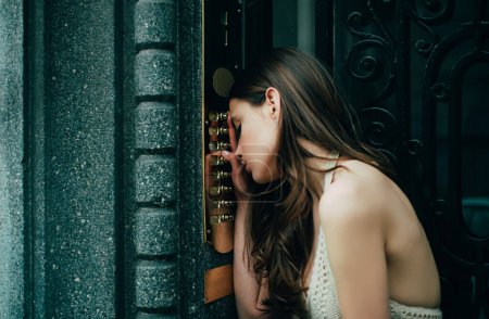 Téléchargez les photos : Femme interphone sonnette à l'entrée du bâtiment. Jeune robe femelle entrant le code sur le clavier de porte - en image libre de droit