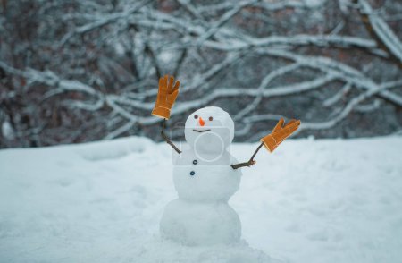 Foto de Feliz invierno. Muñeco de nieve el amigo está de pie en sombrero de invierno y bufanda con nariz roja. Feliz muñeco de nieve divertido en la nieve. Hacer muñeco de nieve y diversión de invierno - Imagen libre de derechos