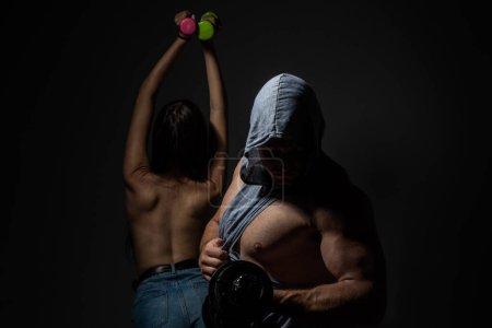 Foto de Pareja deportiva haciendo ejercicio con mancuerna. Chica sexy delgada y saludable con fuerte entrenamiento muscular del hombre - Imagen libre de derechos