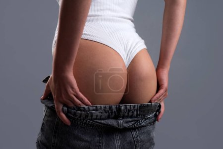 Foto de Closeup photo of sexy slim woman putting on blue jeans. Young girl with sexy body taking off clothes ready to make love, have sex. Sexy ass, butt or buttocks - Imagen libre de derechos
