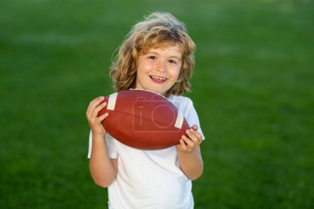 Photo for Outdoor kids sport activities. American football. Portrait of boy holding american football ball in park. - Royalty Free Image