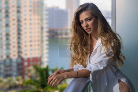 Téléchargez les photos : Femme riche profitant du matin sur le balcon dans des appartements de luxe à Miami. Concept de vie de luxe. Sexy femme sensuelle jouit de repos. Style de vie urbain. Style de vie de détente pendant les vacances d'été - en image libre de droit