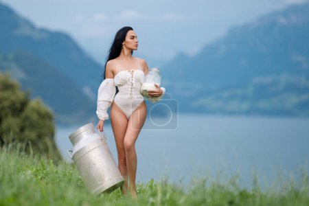 Téléchargez les photos : Ferme laitière. Concept de traite. Lait naturel et biologique. Femme avec du lait frais à la campagne. Ferme laitière en Suisse Alpes. Belle femme aime le lait sur le village alpin dans les montagnes. Alpes laiteuses - en image libre de droit