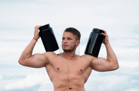 Foto de Nutrición deportiva. Hombre muscular con proteínas, fuertes abdominales masculinos desnudos del torso - Imagen libre de derechos