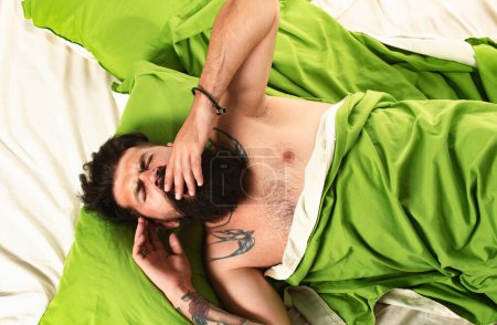 Foto de Foto de hombre guapo durmiendo y sosteniendo almohada verde suave. Buenos días. Feliz de dormir. Hombre durmiendo en la almohada en la cama en casa - Imagen libre de derechos