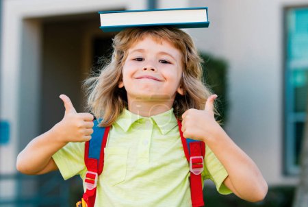 Foto de Retrato de niño lindo de escuela con gafas y una camisa con libro de asideros. Colegial nerd al aire libre - Imagen libre de derechos