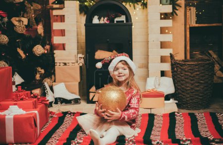 Foto de Retrato de una linda chica feliz en el árbol de Navidad, esperando el año nuevo, sentada junto al árbol de Navidad - Imagen libre de derechos