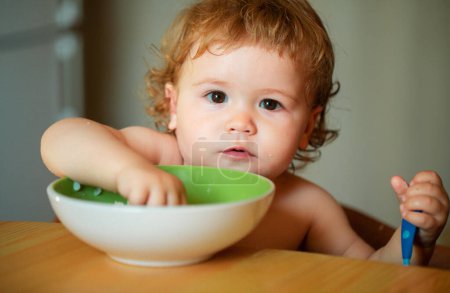 Foto de Retrato de un niño divertido comiendo de un plato sosteniendo la cuchara de cerca - Imagen libre de derechos